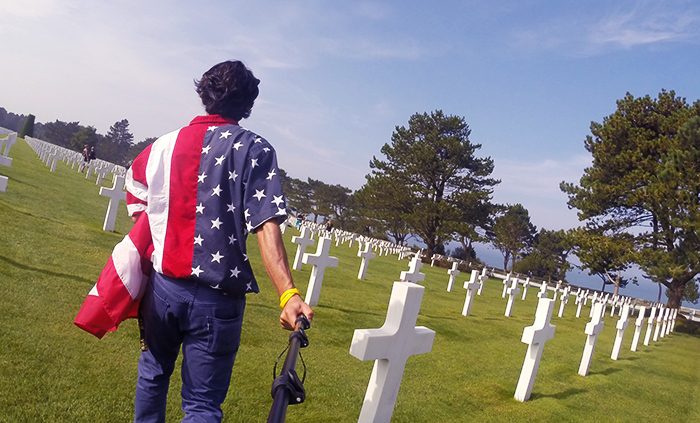 Azimi walks through the American Cemetary at Omaha Beach, capturing his experience on a GoPro camera.