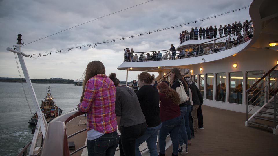 Students look on as the MV Explorer throws her lines and the tugboat begins to pull the ship into the channel for a full 180-degree turn. 