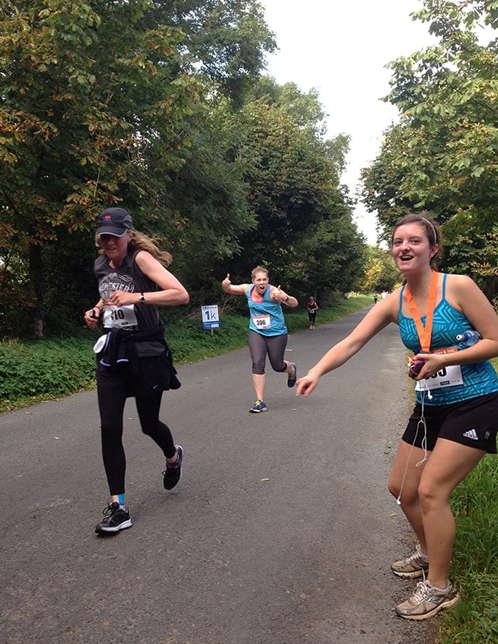 Mary McGehee (right), cheers on teaching assistant Jacqueline Welch (left) and Quincey Shelton (center) as they sprint of the final hill in the race.