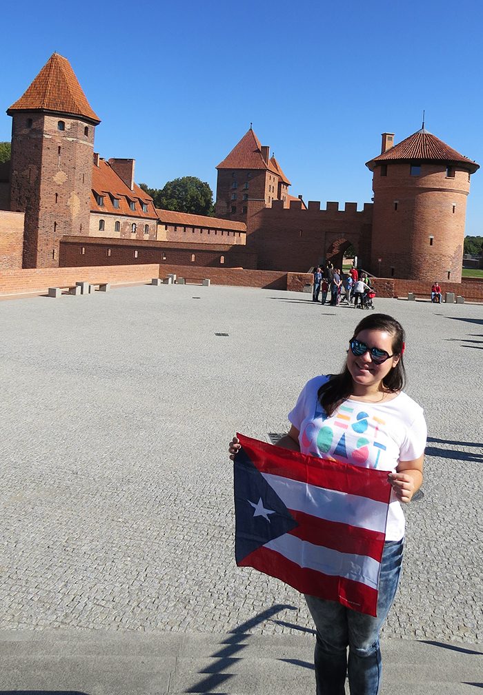 Torres-Cruz stands outside the Malbork Castle in Poland displaying her Puerto Rican flag.