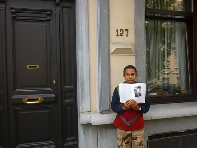 Max Mongosso displays his grandmother's book outside the apartment in Brussels where she hid to avoid Nazi capture.