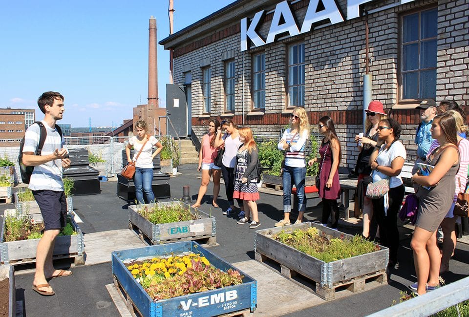 Students hear from a volunteer involved with this rooftop garden at an old cable factory that's been transformed into a cultural center and office space.
